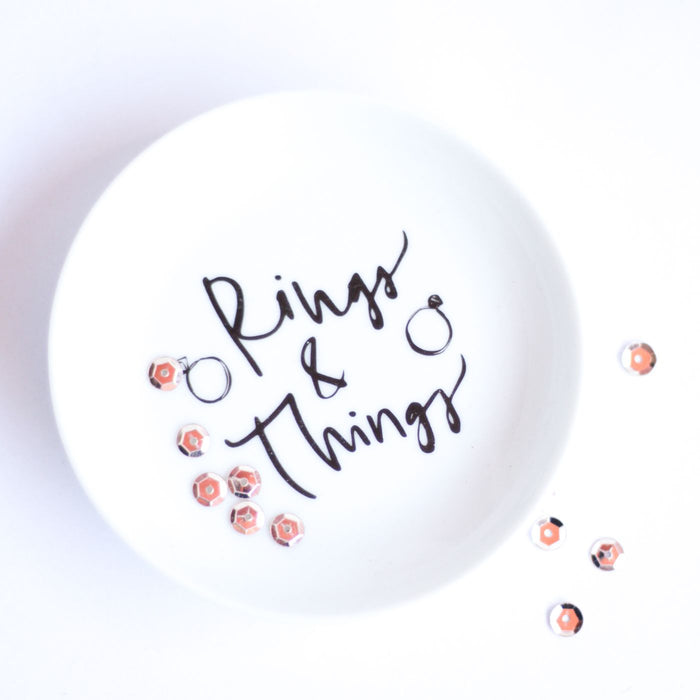 A white dish lettered Rings and Things, photographed on a white background.