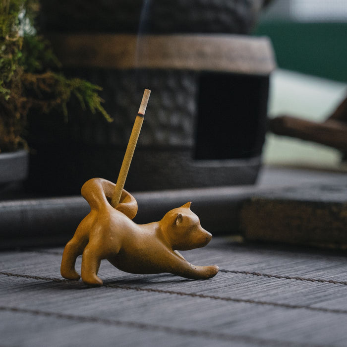 A clay incense holder shaped like a fox, photographed on a wooden table.