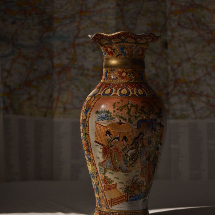 A Japanese porcelain vase with an intricate design, photographed in front of a paper map.