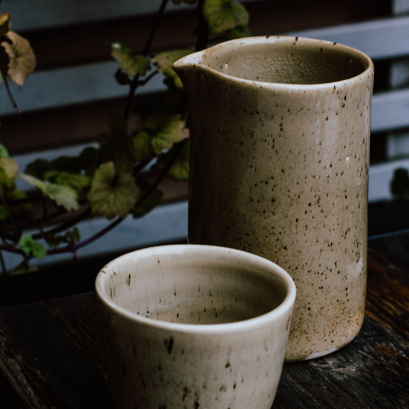A modern ceramic jug and a cup placed together on a wooden table.