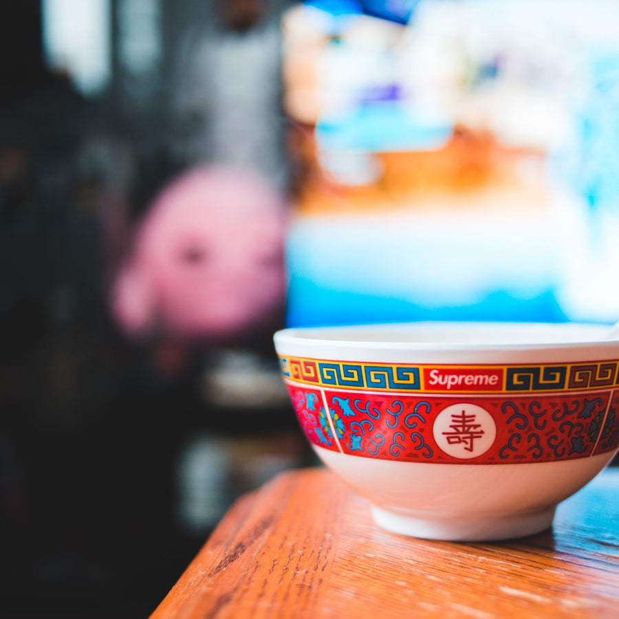 A colourful bowl in an Asian style, photographed on a wooden table with the background thrown out of focus.