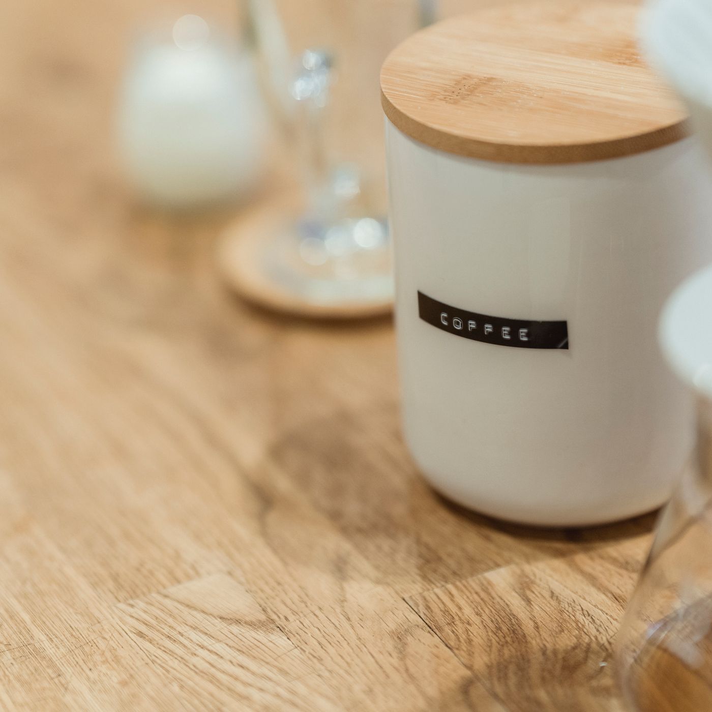 A ceramic coffee jar with a wooden lid, photographed close up on a table.