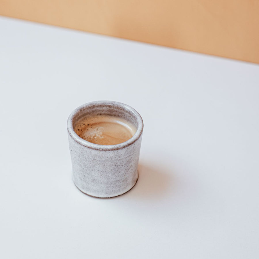 A plain ceramic coffee cup on a white table.