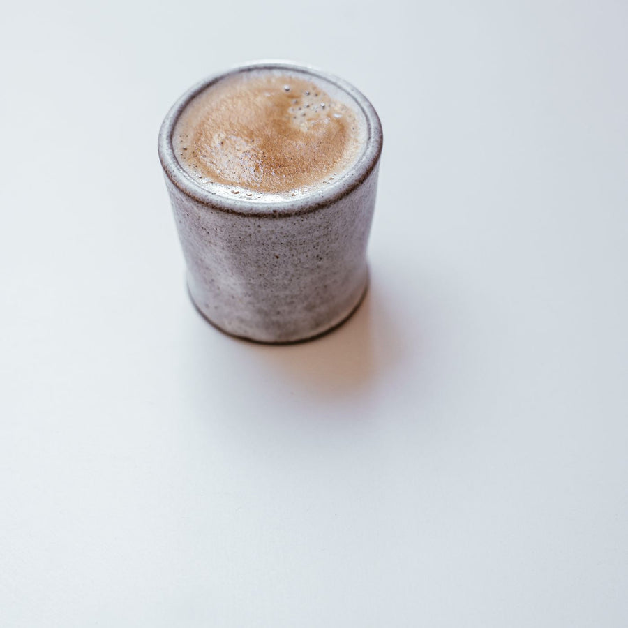 A simple ceramic coffee cup on a clean white surface.