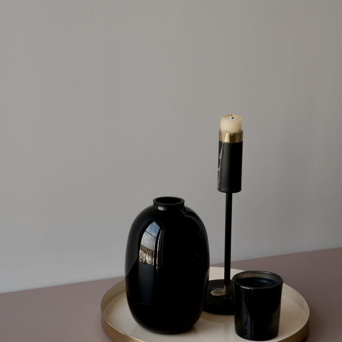 A decorative vase photographed with a few accessories set around it.